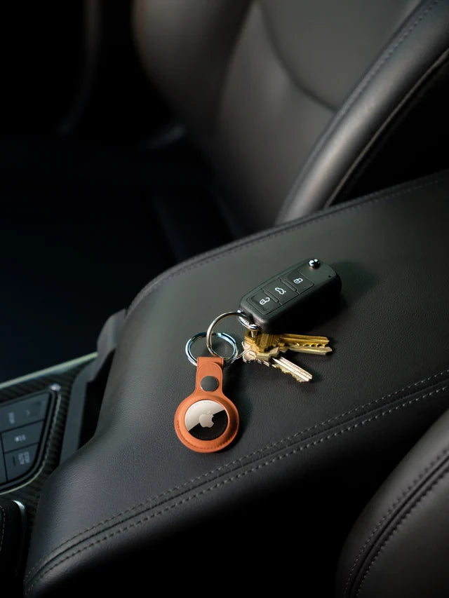 Keys with AirTag in an orange key ring inside a car